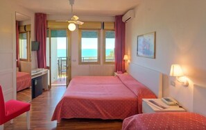 Quarto com cama, escrivaninha, cadeira, mesa pequena com abajur e janela com cortinas.