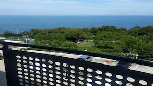 Een balkon met uitzicht op zee en groen.