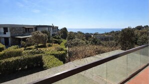 Ein modernes Gebäude mit einer Stein-Fassade, einem Glasbalkon und Blick auf das Meer.
