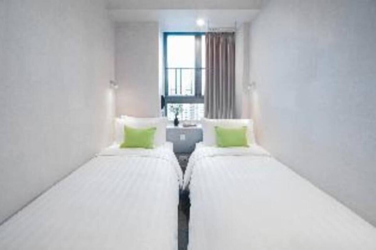 Habitació d'hotel amb dos llits individuals, una taula petita i una finestra amb cortines.