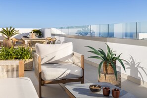 A rooftop terrace with a seating area, including a cushioned chair and a table with drinks and a bowl. - Panorama Luxury Penthouse in Higueron (Benalmádena)