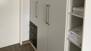 Un armario con puerta, dos cajones y un estante con toallas dobladas.