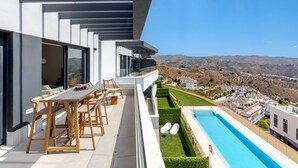A modern outdoor terrace with a pool, seating area, and a view of the surrounding landscape. - Bali in Rincón | Elegant 2BR Apartment with Terrace & Ocean Views (Rincón de la Victoria)