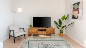 A modern living room with a flat-screen TV, a sofa, a coffee table, and a potted plant. - Bali in Rincón | Elegant 2BR Apartment with Terrace & Ocean Views (Rincón de la Victoria)