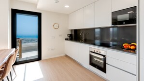 A modern kitchen with a view of the ocean, a dining area with a table and chairs, and a large window. - Bali in Rincón | Elegant 2BR Apartment with Terrace & Ocean Views (Rincón de la Victoria)