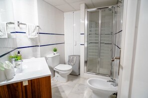 Ein modernes Badezimmer mit Waschbecken, Toilette und Duschbereich in Weiß.
