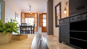 Een moderne keuken met een donker kastje, een houten eettafel met stoelen en een potplant.
