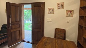 A room with a wooden dining table, a chair, and a bench. There are three framed pictures on the wall. - Bluewoods Homestay – Serene Retreat Near Kochi City (Ernakulam)