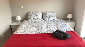A bed with alphabet-patterned bedding, two bedside tables, and a red bedspread. - Holiday Home 'Sunshine Home - 300m To The Beach' with Sea View, Private Terrace and Wi-Fi (Leça da Palmeira)
