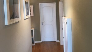 A hallway with a white door, framed pictures on the wall, and a pendant light. - Holiday Home 'Sunshine Home - 300m To The Beach' with Sea View, Private Terrace and Wi-Fi (Leça da Palmeira)