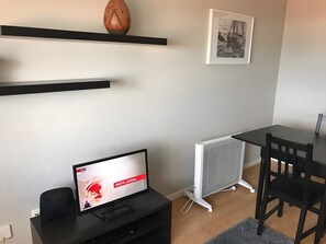 Un salon moderne avec un téléviseur à écran plat, un radiateur, une table à manger et une chaise noire.