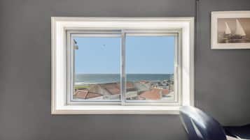 Habitación con un amplio ventanal con vistas al litoral, un cuadro en la pared y una silla.