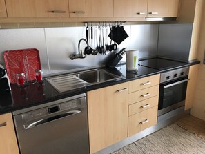 Une cuisine moderne dotée d’appareils électroménagers en acier inoxydable, de meubles en bois et d’un plan de travail noir.