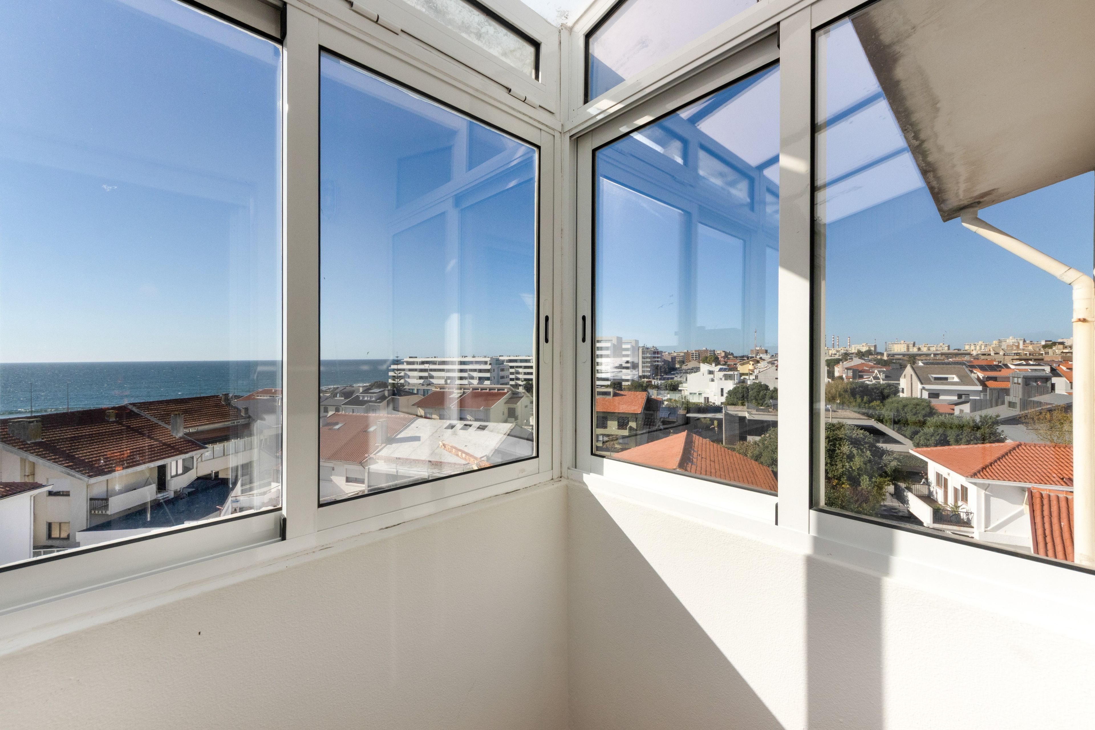 A corner of a room with large windows overlooking a coastal cityscape.
