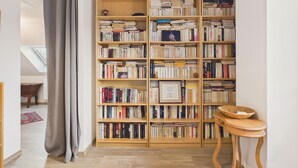 A room with a large wooden bookshelf filled with books, a wooden table with a basket, and a grey curtain. - House for 6 with garden, St Gildas town centre (Saint-Gildas-de-Rhuys)