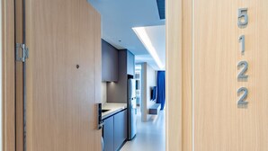A hotel corridor with wooden doors, a kitchenette, and a blue curtain. - Beachfront 5122 Building C Modern 2BR Suite (Choeng Thale)