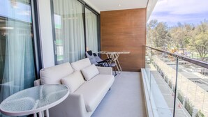 Un balcon avec un canapé, une petite table et un étendoir.
