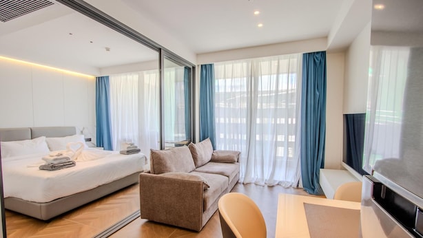 Une chambre d’hôtel moderne équipée d’un lit, d’un canapé, d’une télévision et d’un coin repas.