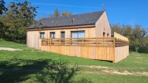 Une maison en bois avec un toit en pente, une cour clôturée et un petit jardin.