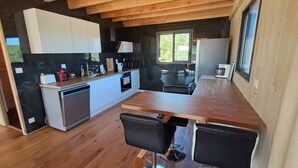 Une cuisine moderne avec un plan de travail en bois, des armoires blanches et un crédence noire. On y trouve également un coin repas avec deux chaises et une table.
