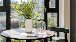Une table ronde ornée d’une fougère en pot, de deux bouteilles d’eau, d’une bougie blanche et d’un bloc-notes.