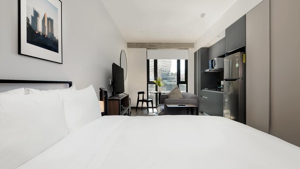 Une chambre d’hôtel avec un grand lit, un bureau avec une chaise, une télévision et un réfrigérateur.