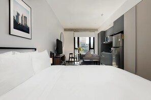 Une chambre d’hôtel avec un grand lit, un bureau avec une chaise, une télévision et un réfrigérateur.
