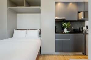 Ein modernes Hotelzimmer mit Bett, einer Küchenzeile und einem Einbauschrank.