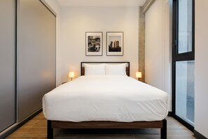 A modern hotel room with a large bed, two framed pictures on the wall, and a window with a view of the city. - w Appealing Loft in the Heart of Interlomas (Huixquilucan)