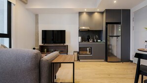 A modern living space with a sofa, a small table, a TV, a kitchen area with a fridge, microwave, and cabinets. - w Appealing Loft in the Heart of Interlomas (Huixquilucan)
