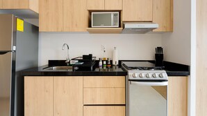 A modern kitchen with wooden cabinets, a microwave, a stove, a sink, and various kitchen items. - w Deluxe Loft w/ Balcony in Tabacalera (Mexico City)