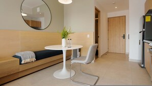 A modern, well-lit room with a round table, a bench, and a chair. A mirror hangs on the wall, and a door leads to another room. - w Deluxe Loft w/ Balcony in Tabacalera (Mexico City)