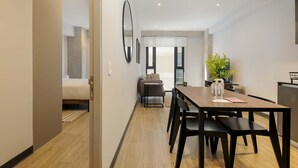A modern hotel room with a wooden dining table, black chairs, a sofa, and a large mirror. - w Amazing 1BR in the Heart of Interlomas (Huixquilucan)