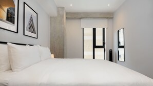A modern hotel room with a large bed, framed pictures on the wall, and a view of the city through a large window. - w Amazing 1BR in the Heart of Interlomas (Huixquilucan)