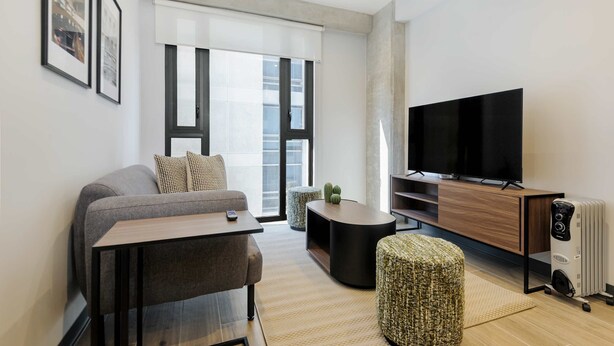 A modern living room with a sofa, a coffee table, a TV, and a radiator. - w Amazing 1BR in the Heart of Interlomas (Huixquilucan)