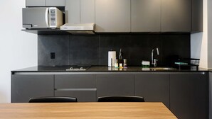 A modern kitchen with dark cabinetry, a microwave, a stove, and a sink.