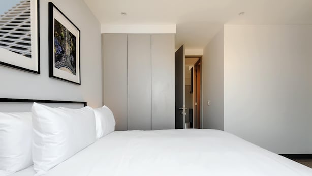 A modern bedroom with a large bed, a wardrobe, and a framed picture on the wall. - w Luxurious 2BR in the Heart of Interlomas (Huixquilucan)