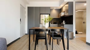 A modern kitchen with dark cabinetry, a wooden dining table, and black chairs. - w Luxurious 2BR in the Heart of Interlomas (Huixquilucan)