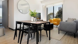 A modern living room with a dining area, a sofa, a TV, and a large window with a city view. - w Luxurious 2BR in the Heart of Interlomas (Huixquilucan)