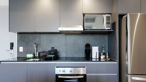 A modern kitchen with grey cabinets, a built-in microwave, a stainless steel refrigerator, and a small oven. - w Charming 2BR in the Heart of Interlomas (Huixquilucan)