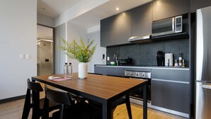 A modern kitchen with a wooden dining table, black chairs, a microwave, and a refrigerator. - w Charming 2BR in the Heart of Interlomas (Huixquilucan)