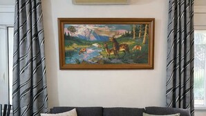 A living room with a sofa, a painting of deer, and patterned curtains. - Zografou Cozy Apartment in the heart of Athens! (Zografou)