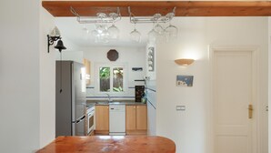 A kitchen with a wooden countertop, a refrigerator, a dishwasher, and a hanging light fixture. - Villas 2meet La Yuca – Holiday Home with Private Pool in Cala Romántica, Mallorca (Romàntica)