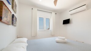 A bedroom with a bed, a window, a flat-screen TV, and artwork on the wall. - Villas 2meet La Yuca – Holiday Home with Private Pool in Cala Romántica, Mallorca (Romàntica)