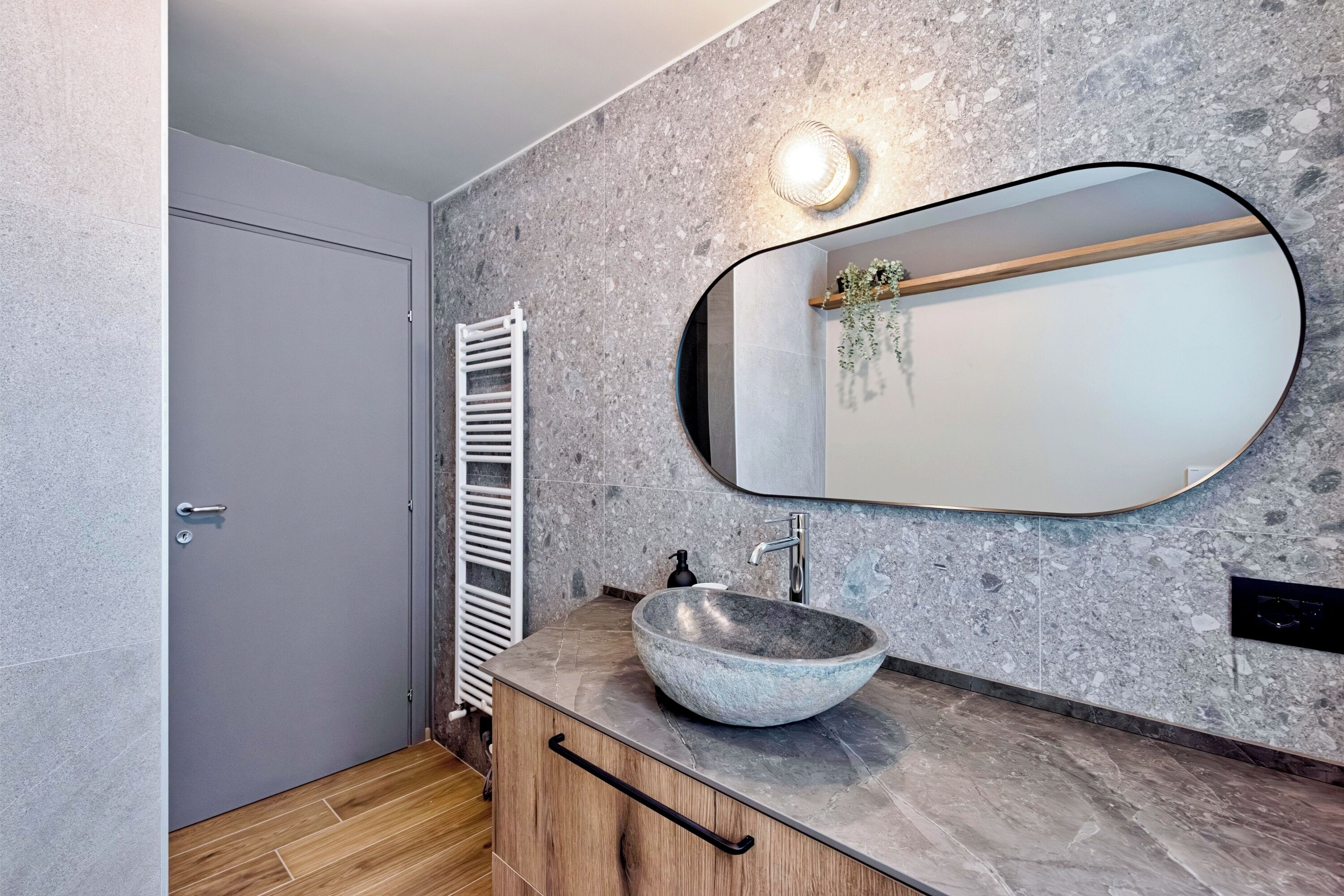 A bathroom with a stone sink, a mirror, a towel rack, and a wooden cabinet.