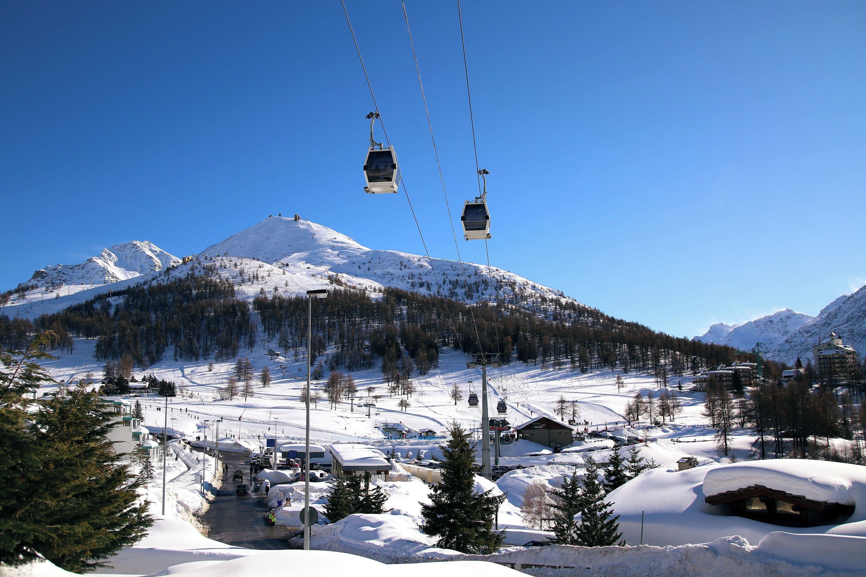 Una muntanya coberta de neu amb telesquí i edificis a la base.