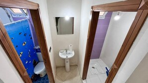 Ein kleines Badezimmer mit einem weißen Waschbecken, einem Spiegel und einer Toilette.