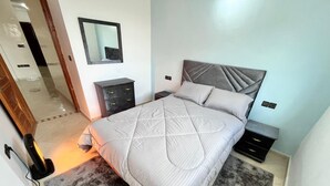Ein Schlafzimmer mit Bett, Nachttisch, Kommode, Spiegel und Heizung.