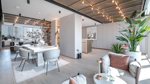 A spacious living area with a dining table, seating, and a large plant. - Stayshort - Elegant Studio Living in JVC Perfect for 2 (Dubai)