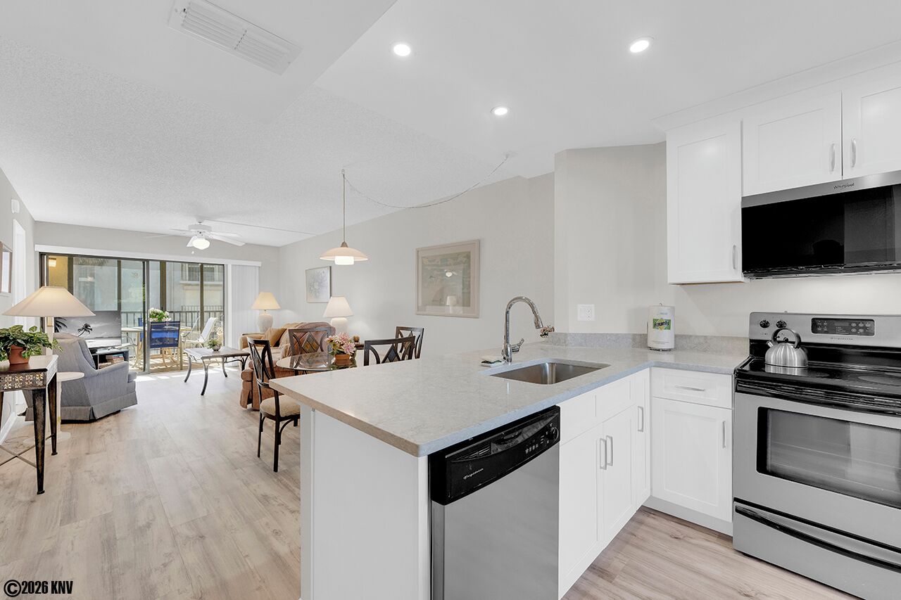 A modern kitchen with white cabinetry, a built-in dishwasher, and a stainless steel oven.